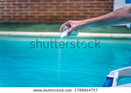 Person cleaning and chlorinating the pool on a hot summer afternoon, is running the cleaner and adding chlorine powder Royalty-Free Stock Photo #1788864797