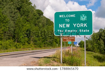 The Welcome to New York state line sign on US Route 62 in Chautauqua County, New York, USA on a sunny summer day