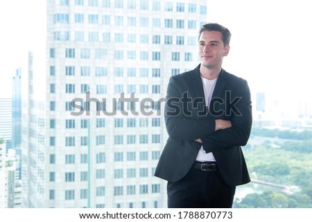 Portrait business partner executive smart man smiling and standing in modern office. Young people businessman thinking him work and relax time.  City background.  Teamwork and Business Concept
