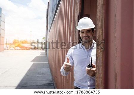 Handsome young engineers using walkie-talkie for communication to control the transportation of products through containers on the job site. Professional supervisor for new business and big projects.