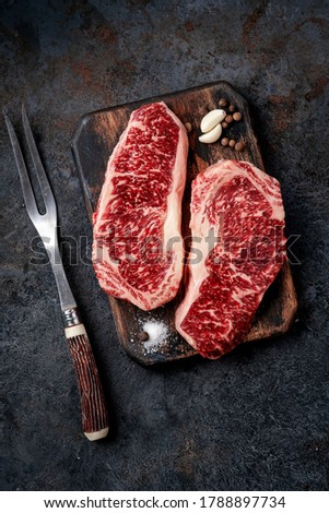 Two raw new York steaks on a chopping Board with meat fork. Wagyu meat for grilling, top view Royalty-Free Stock Photo #1788897734