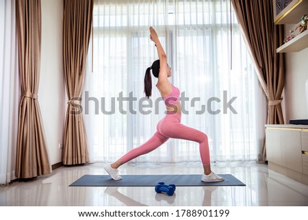 Asian woman's fitness workout at home .Her learning new exercises watching online workout tutorials over her at home.