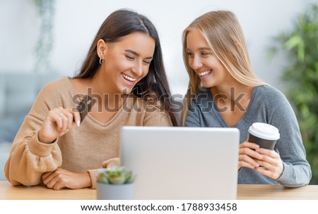 Two happy young women doing online purchases. Girls doing shopping at home.