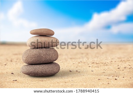 Pyramid stones balance on the sand of the beach.