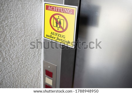 yellow service sign with German text for ELEVATOR OUT OF SERVICE attached to elevator door, digital composite