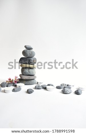 Stack stones isolated in white background and pink wax flowers. Pebbles tower. Concept of balance and harmony. Blur