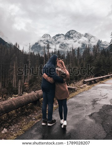 A couple in love, a guy and a girl are embracing against the backdrop of mountains. Snow-covered tops of mountains and dry conifers in the fog. Morskie oko