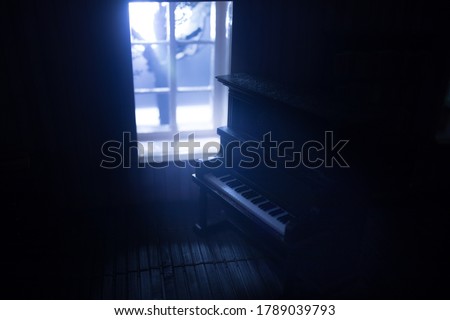 A realistic dollhouse living room with furniture and window at night. Old toy piano in dark room. Selective focus.