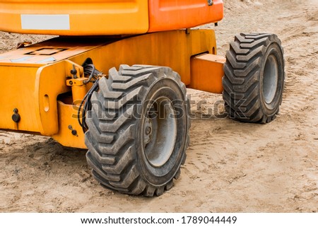 Wheels of industrial lifting transport against the background of sand at a construction site