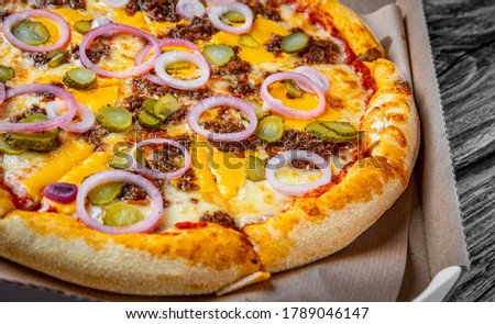 Pizza with Mozzarella cheese, Bolognese sauce, minced meat and vegetables. Italian pizza in paper box on wooden background.