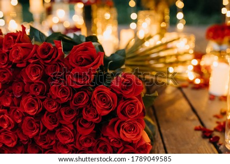 Big bouquet of 101 red roses on background of bright lights in evening.