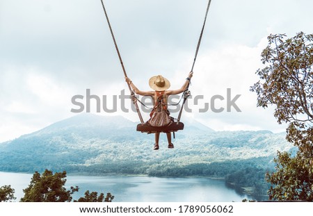 Woman with hat enjoying freedom on a swing in Bali, Indonesia. Life, adventure and peaceful feelings Royalty-Free Stock Photo #1789056062