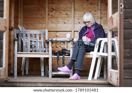 Senior lady in garden shed relaxing in retirement