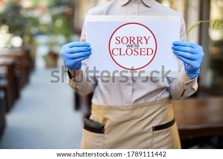 Close-up of cafe owner holding closed sign due to coronavirus epidemic. 