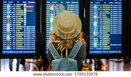 portrait and close up of the back of curly woman checking the time of her flight in the airport to traveling outdoors and enjoy her vacations - noamd lifestyle and concept Royalty-Free Stock Photo #1789133978