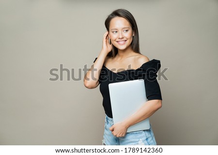 happy cute girl with a laptop in a black jacket with bare shoulders