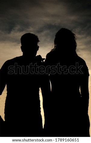 Silhouettes of people, with the sun in the background.