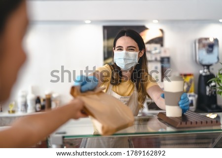 Bar owner working only with take away orders during corona virus outbreak - Young woman worker wearing face surgical mask giving takeout meal to customers - Healthcare and Food drink concept  Royalty-Free Stock Photo #1789162892