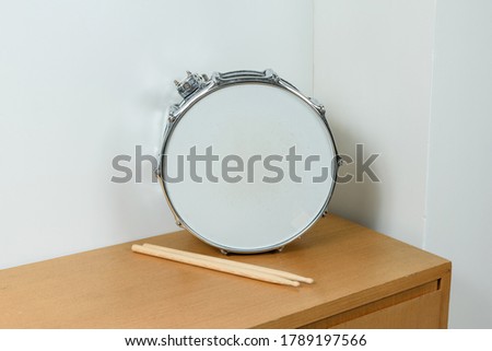 Silver drum snare next to the drumsticks.