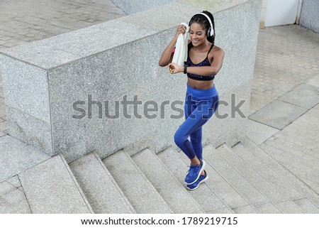 Sportswoman wiping sweat with towel and checking ammount of calories she burned during morning run via app in smartwatch Royalty-Free Stock Photo #1789219715