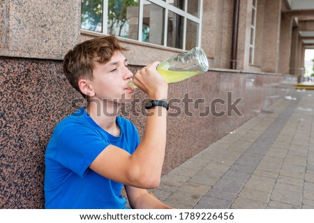 The teenager drinks beer, sitting on the street. The concept of early childhood alcohol addiction Royalty-Free Stock Photo #1789226456