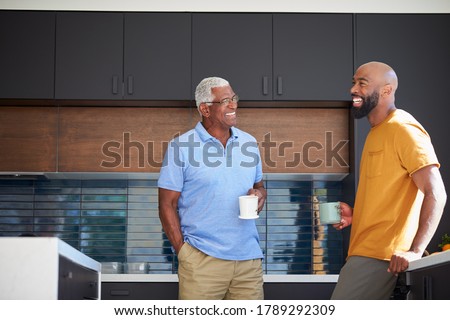 Senior Father Talking And Drinking Coffee With Adult Son In Kitchen At Home Royalty-Free Stock Photo #1789292309