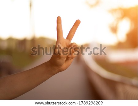 Female hand gesture two thumb up. Sunlight, blurred background.