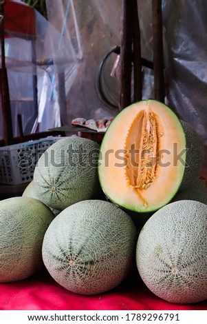 Fresh organic cantaloupe melons stacked on table for sale at market.