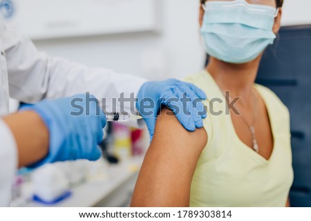 Female doctor or nurse giving shot or vaccine to a patient's shoulder. Vaccination and prevention against flu or virus pandemic.  Royalty-Free Stock Photo #1789303814