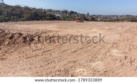 Industrial construction development earthworks site  with grader roller heavy machine moving leveling soil sand in rural countryside panoramic landscape.