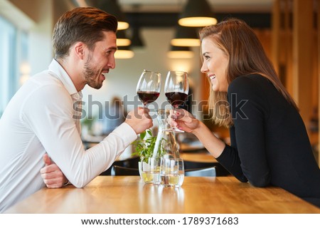 Amorous young couple having a rendezvous at the restaurant drinking a glass of red wine Royalty-Free Stock Photo #1789371683