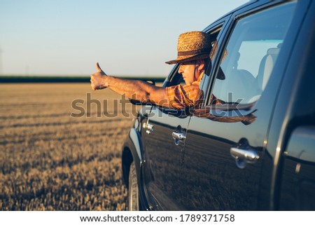 Young man in straw hat driving truck. Life on a farm. 