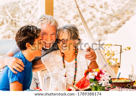 Cheerful happy family celebrate together at lunch hugging and smiling - mixed generations ages with grandfathers and caucasian teenager grandson - social contact for healthy people outdoor