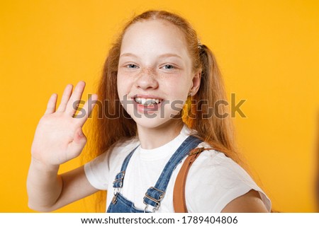 Close up young redhead school teen girl 12-13 years old pony tails in white t-shirt doing selfie shot isolated on yellow background children studio portrait Childhood kids education lifestyle concept.