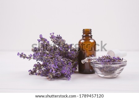Dropper bottle with lavender essential oil and lavender flowers on white background with copyspace for text. Trendy toned photo for your blog or presentation, mockup