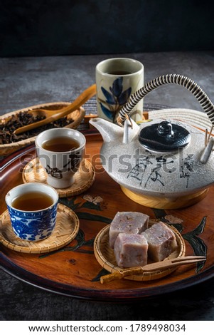 Chinese or Japanese Culture The Oriental traditional drink; Cups of tea served with banana custard teapot on light textured table. Concept of relax, holidays, weekends.