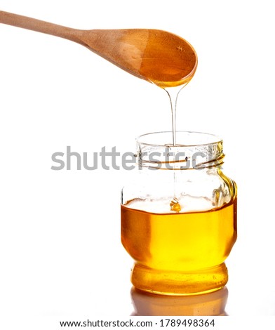 Honey in a glass jar, scoop the honey in a glass jar with a wooden spoon.