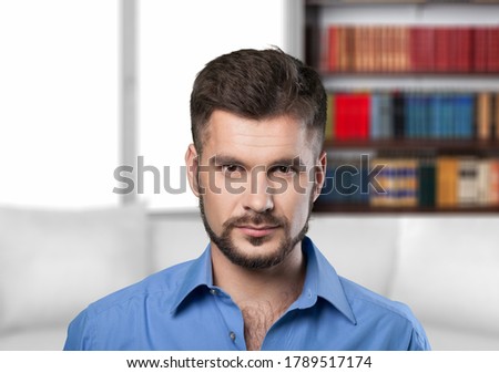 Handsome millennial guy sit on sofa in living room and looks at camera Royalty-Free Stock Photo #1789517174