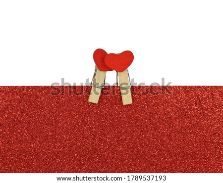 Two clips with heart sitting on glittering red background . Valentine's Day concept.