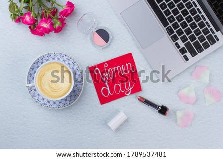 Flat lay women day concept and cup of coffee. Laptop with flowers and cup of coffee on a white table.