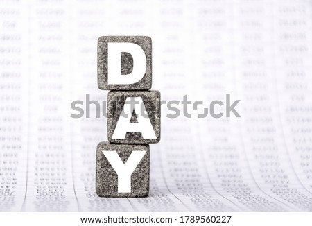 three stone cubes on the background of white financial statements, tables with the word day. Strong business concept