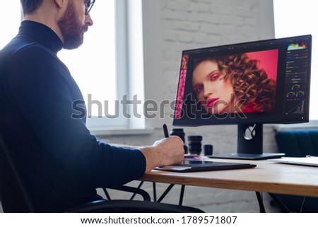 Retouching images in special program.Portrait of graphic designer working in office with laptop,monitor,graphic drawing tablet and color palette.Retoucher workplace in photo studio.Creative agency.