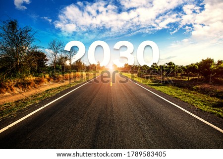 2030 behind the tree of empty asphalt road at golden sunset and beautiful blue sky. Concept for vision year 2030. 