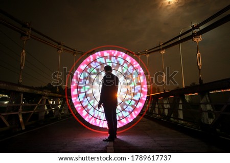 amazing Portrait Indonesian people posing standing alone with colorful circle lightpainting as a backdrop on the bridge 
