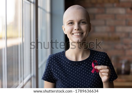 Portrait of smiling sick young Caucasian woman beat breast cancer show red ribbon symbol of disease, happy ill female oncology patient support people with illness, healthcare, recovery concept