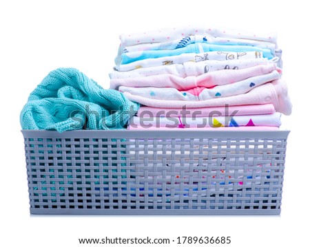 basket with stack baby clothing on white background isolation