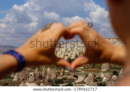 Symbol of heart made up of womens fingers through it is seen Cappadocia, Turkey on cloudy day. Picture with shallow depth of field