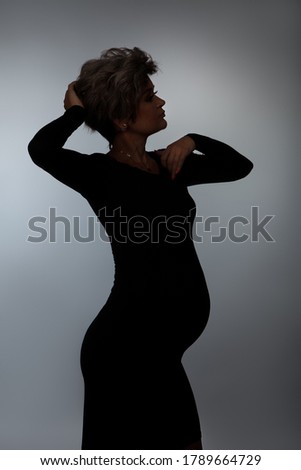 Silhouette of loving pregnant woman looking at camera while posing