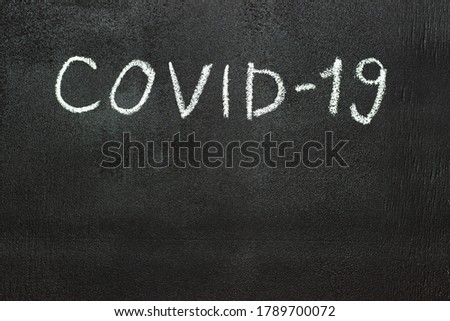 COVID-19 is written in white chalk on a chalk board.