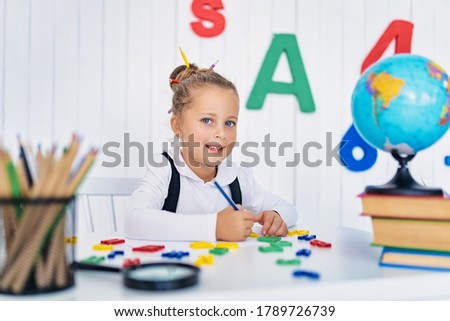 Back to school. Happy smiling pupil at the desk. Child in the class room with pencils, books. Kid girl from primary school. first day of fall.